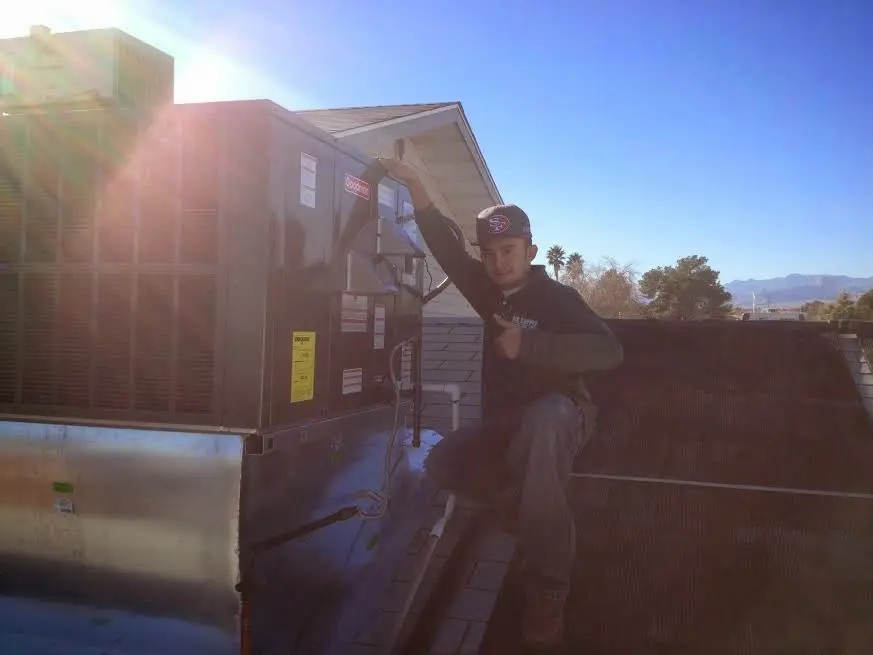 HVAC technician performing Boiler Repair on a rooftop unit in Maize